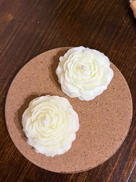 Dos peonías de cera blanca sobre un posavasos de corcho